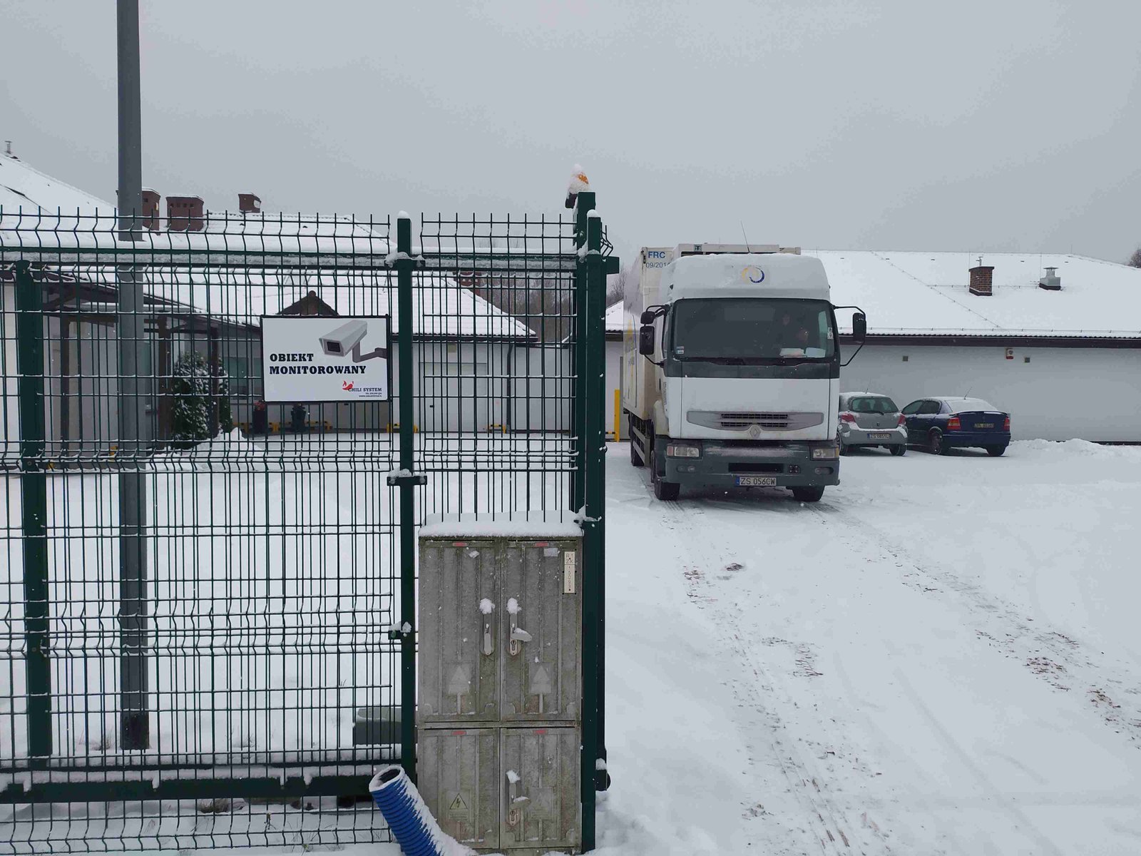 Pracownik na drabinie instalujący kamerę monitoringu na ścianie